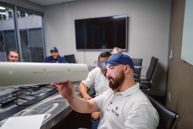 Sewer cleaning company with a plumber looking down a clean sewer pipe.