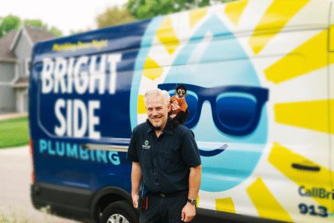 Friendly plumber smiling with monkey on shoulder in front of the Bright Side Plumbing van. | Bright Side Plumbing