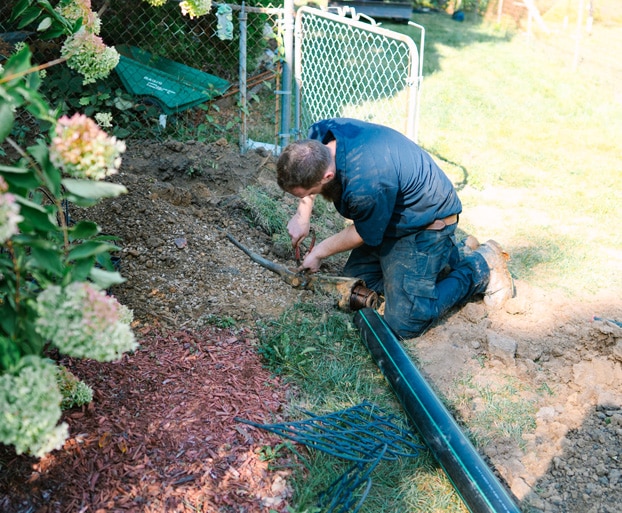 Bright Side Plumbing technician performing trenchless sewer line repair through a small access trench in a Kansas City residential yard.